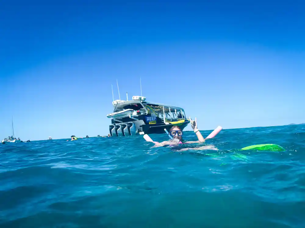 a snorkeller waving at the surface with the vessel anchored behind