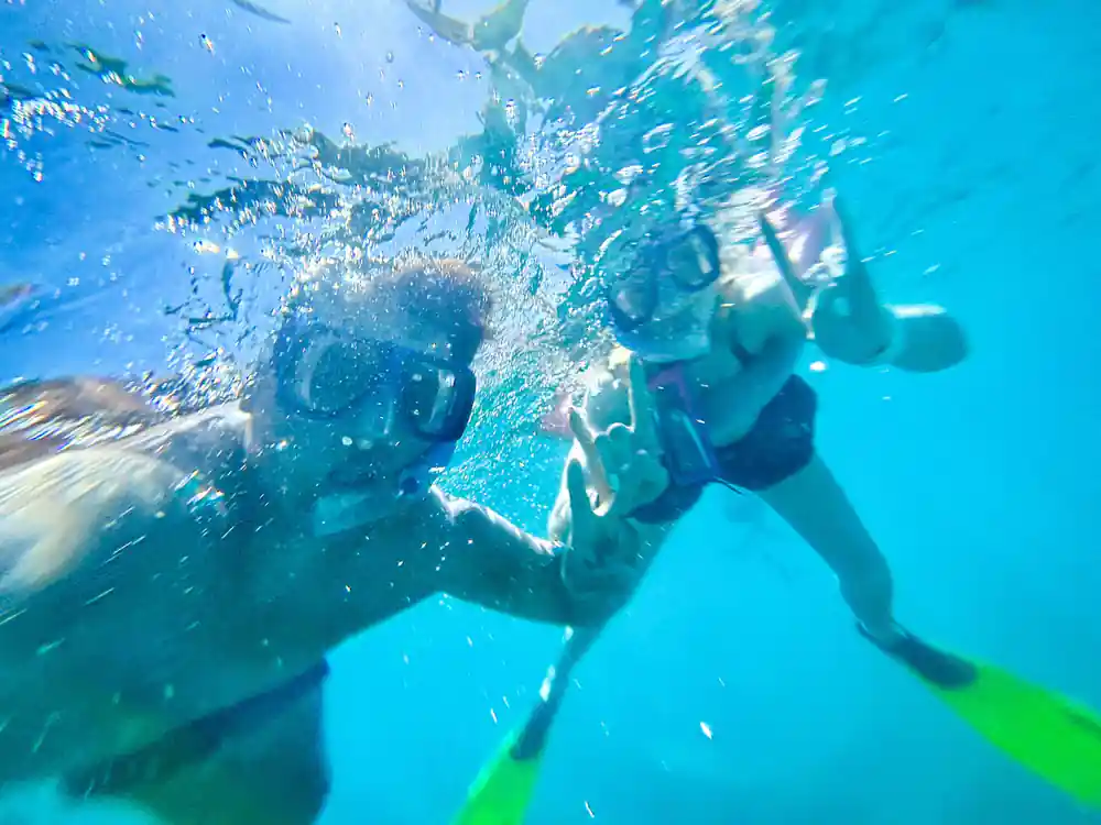 two snorkellers underwater together, fins and masks catching the light